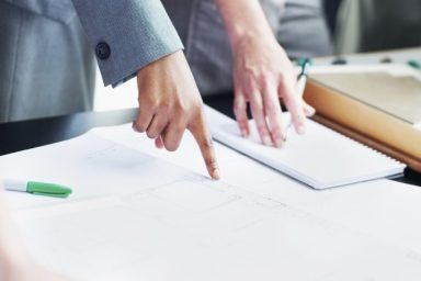 Hands pointing to plans on a table